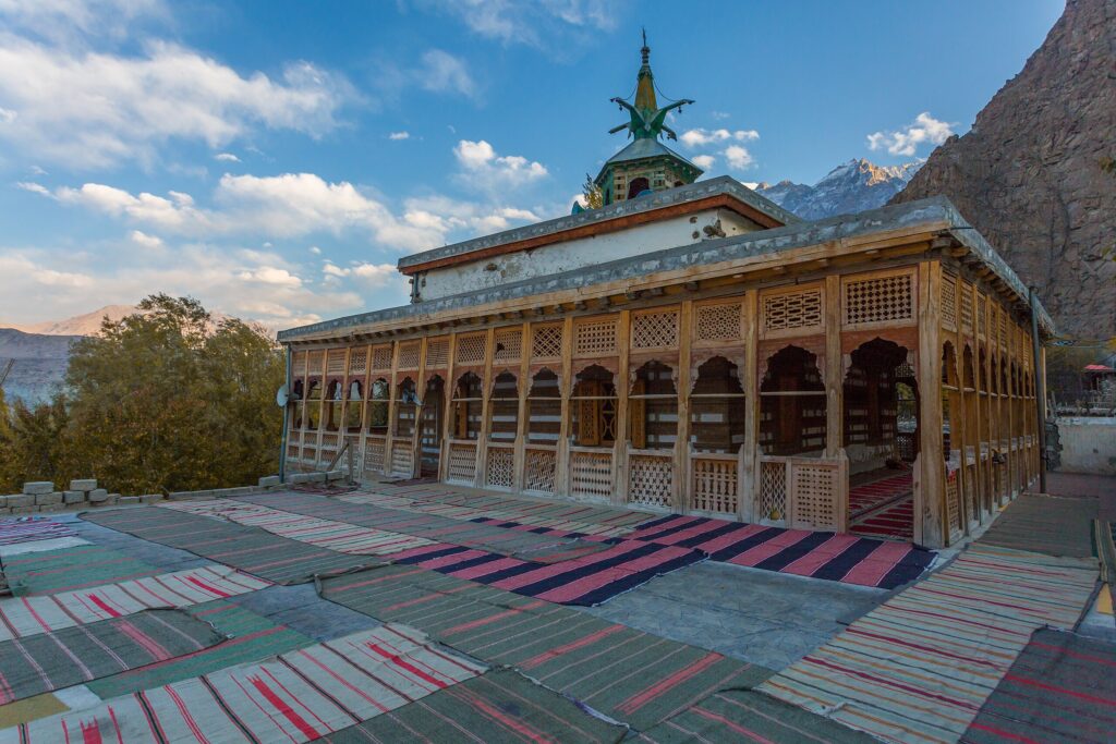 Wooden historic mosque with prayer mats and mountain views in Khaplu