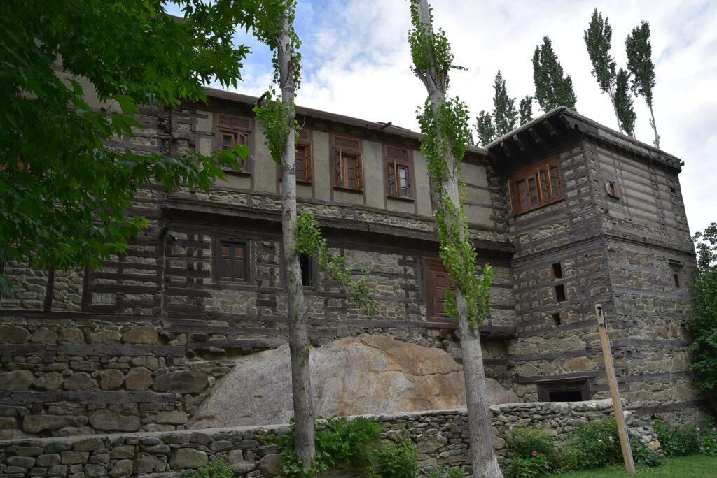 Historic stone and wooden fort surrounded by tall trees