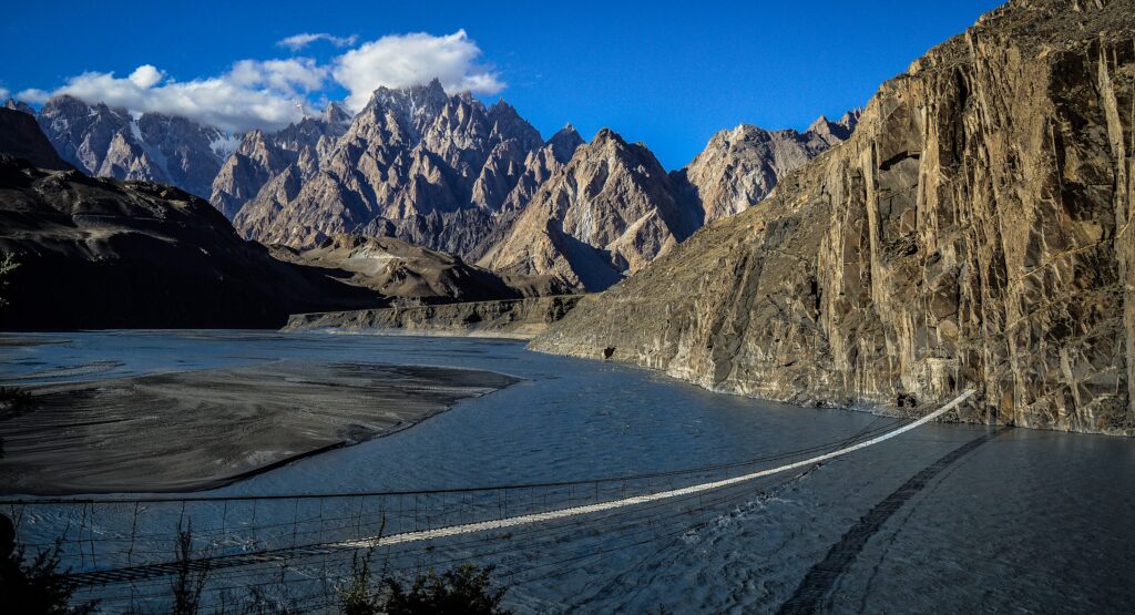 Suspension bridge crossing river with Passu Cones in the background